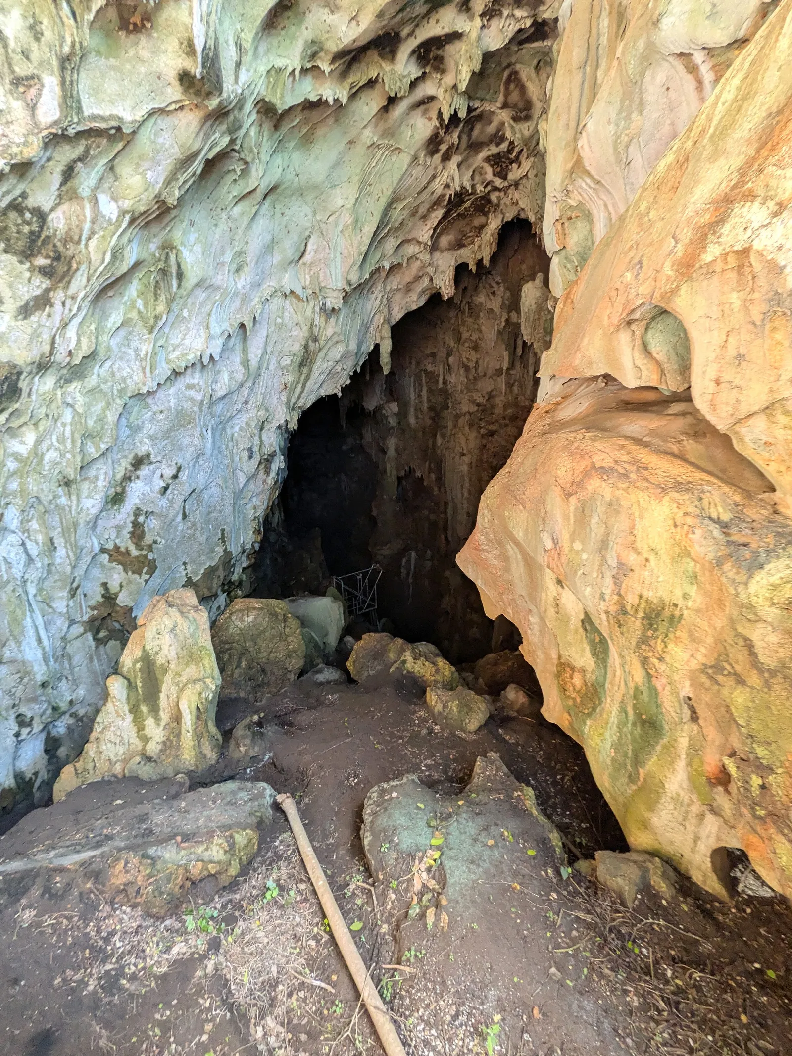 The mouth of Kalabera Cave, a wide limestone opening streaked with mineral colour and hung with stalactites