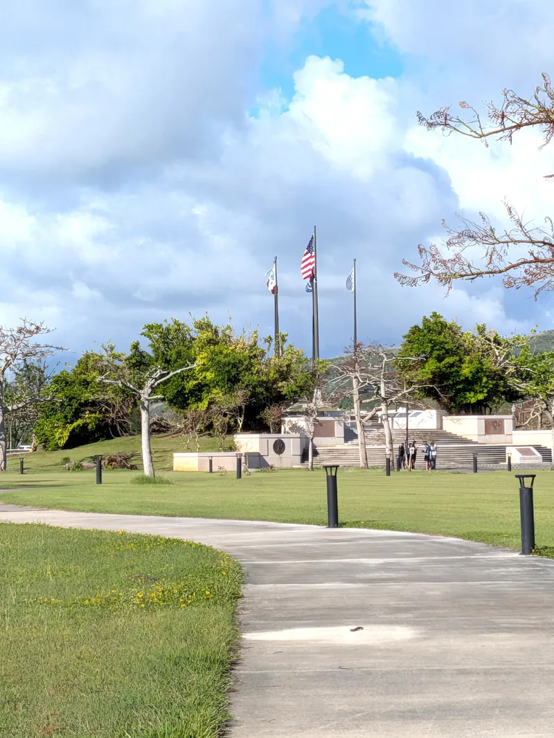 The Court of Honor at American Memorial Park, Garapan, with flags at half-mast and visitors at the granite panels