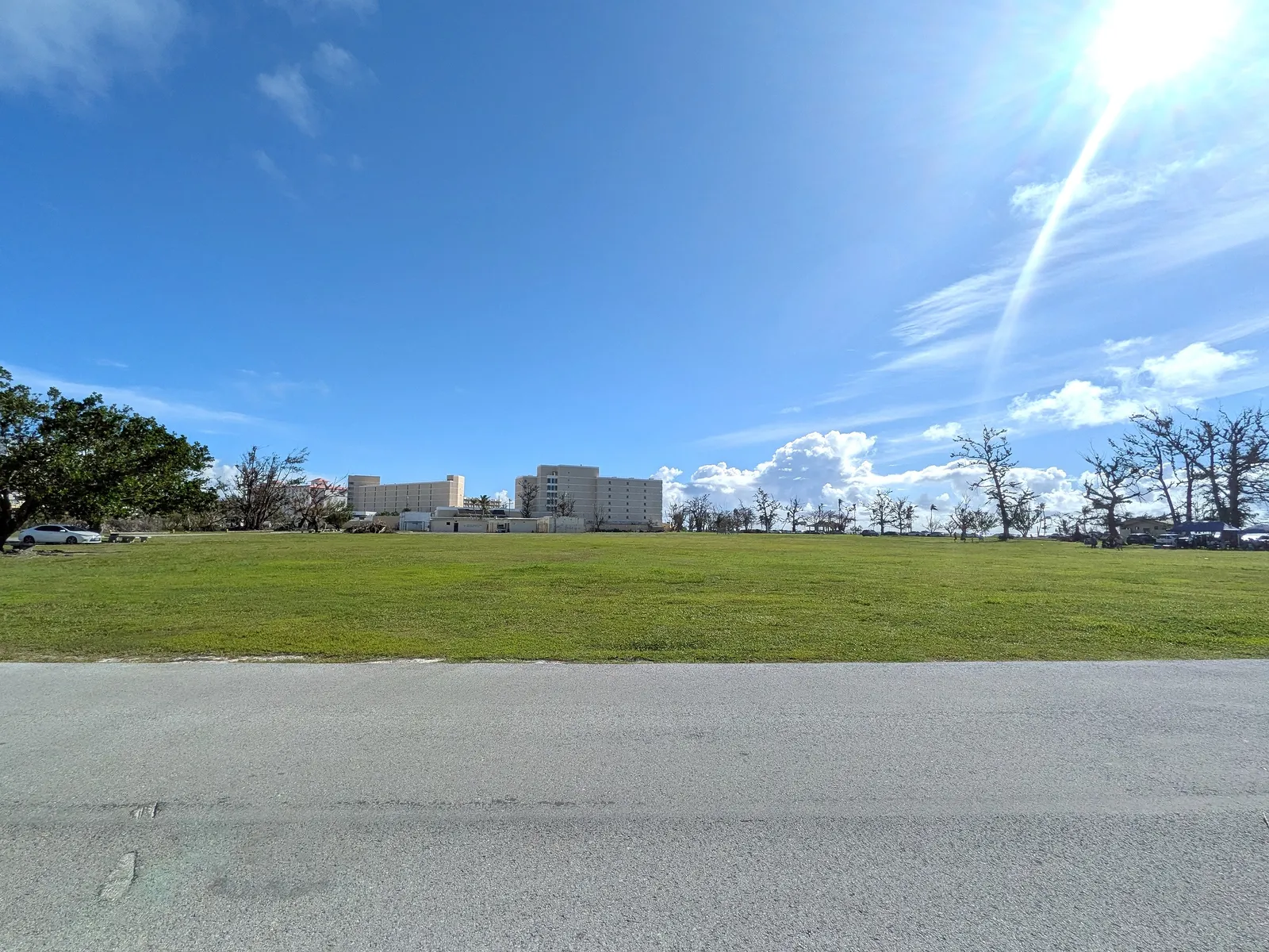 Micro Beach's grassy green with the Hyatt Regency Saipan visible beyond the parking area