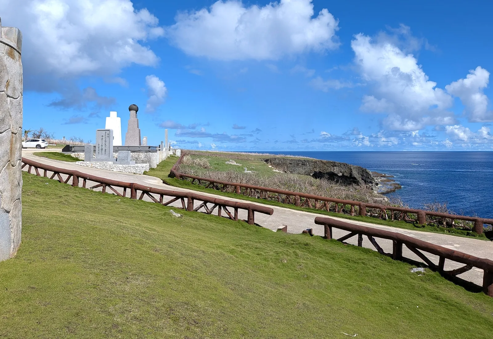 The paved clifftop path at Banzai Cliff running past the monuments, with railings along the seaward edge