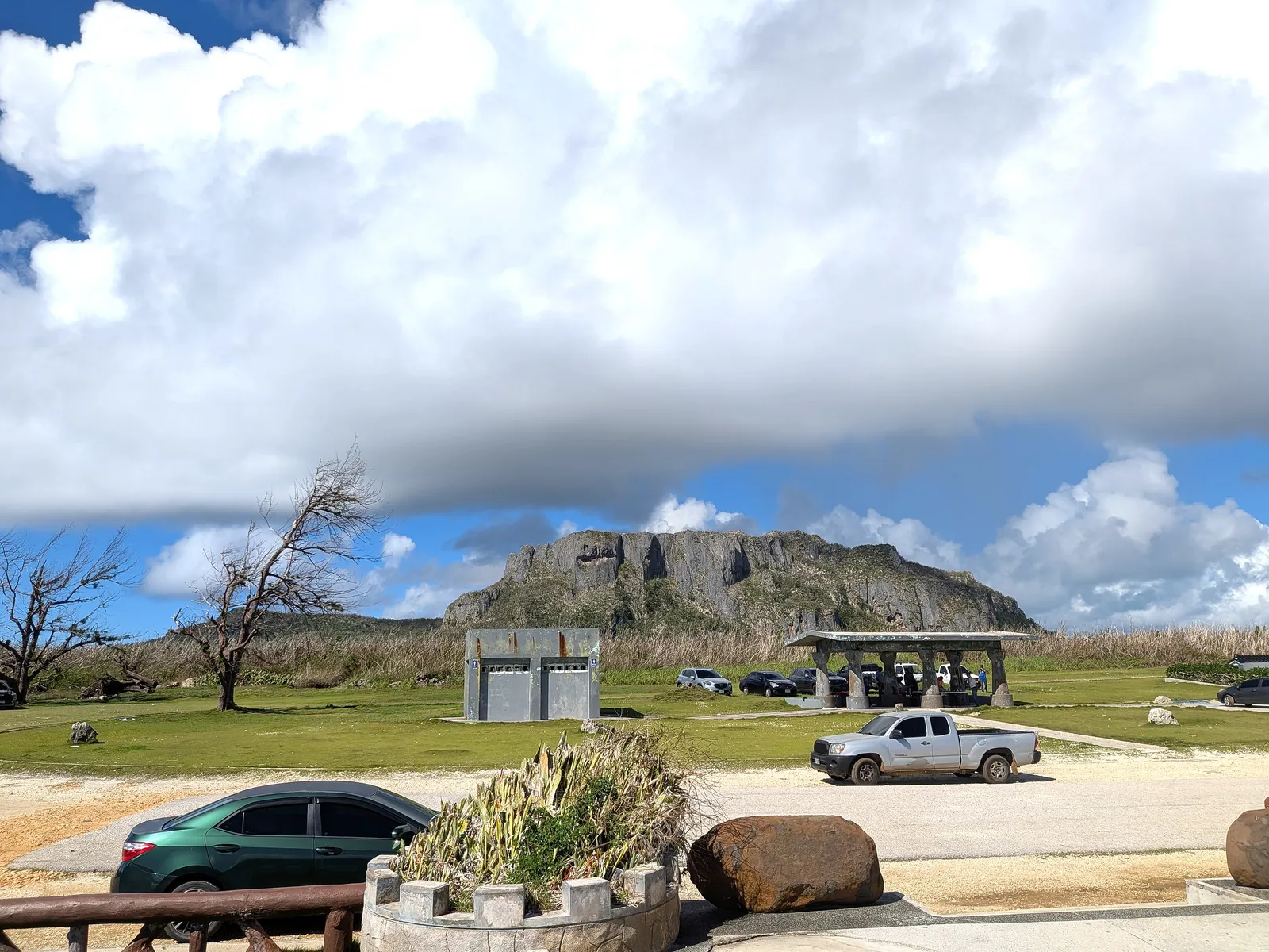 The parking area at Banzai Cliff with a restroom block and covered pavilion, and the limestone mass of Suicide Cliff rising behind