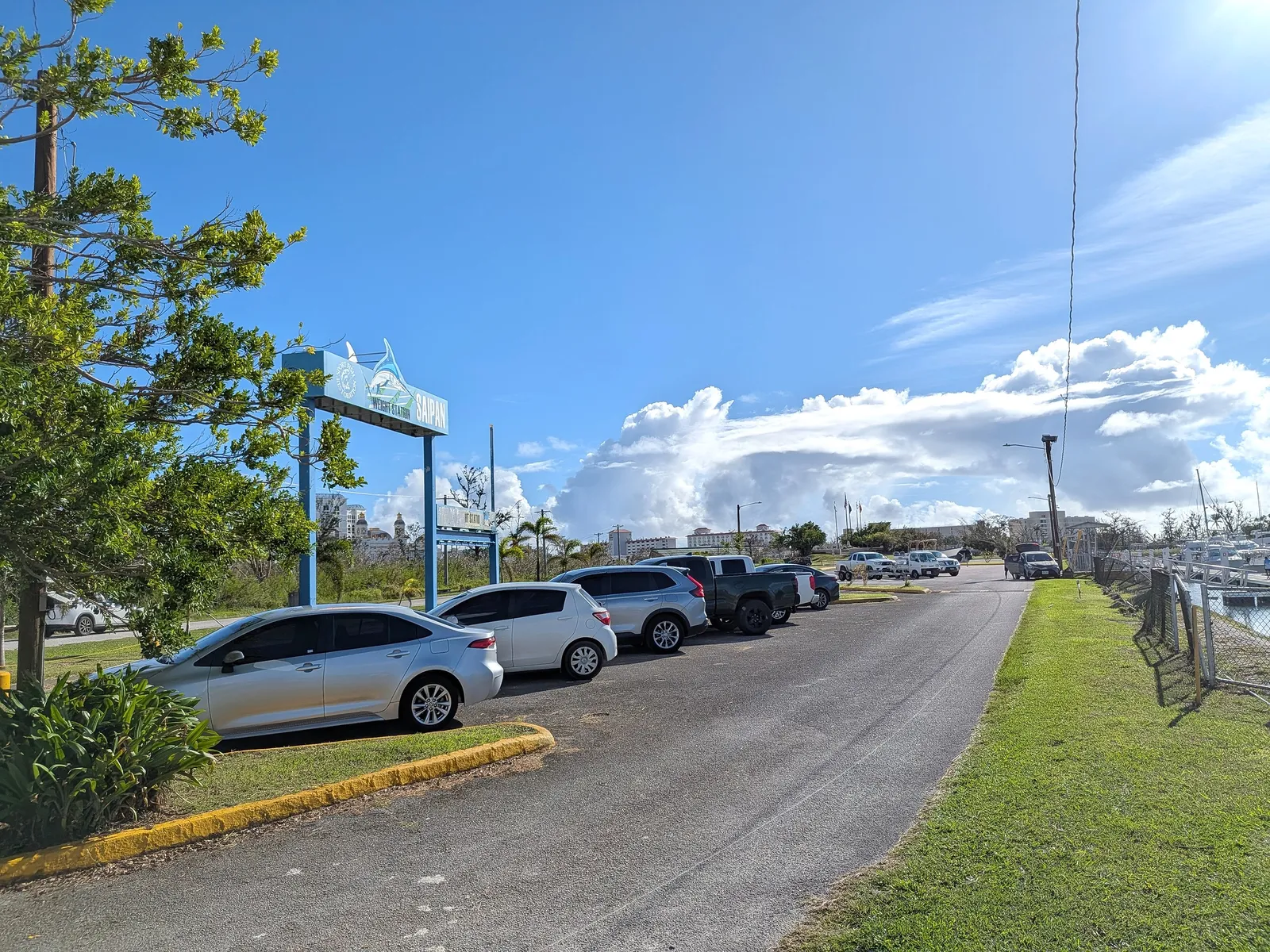 Cars parked along the marina road at Smiling Cove beneath a sportfishing weigh station sign