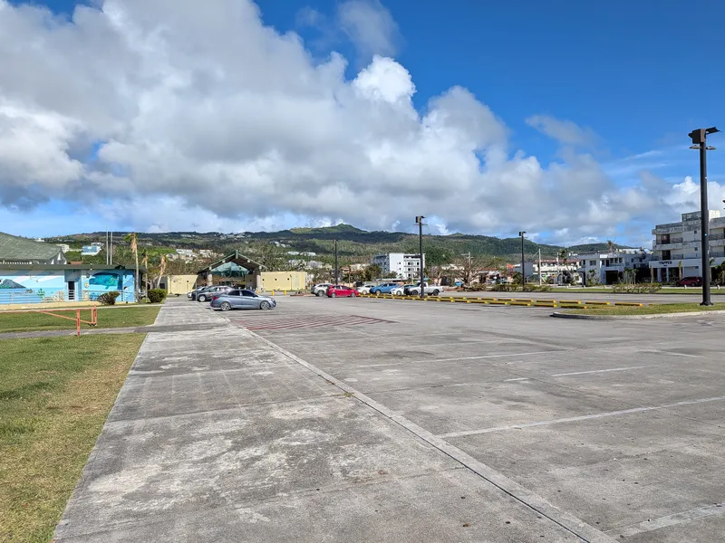 Parked cars near the American Memorial Park visitor center, with Garapan buildings visible in the background