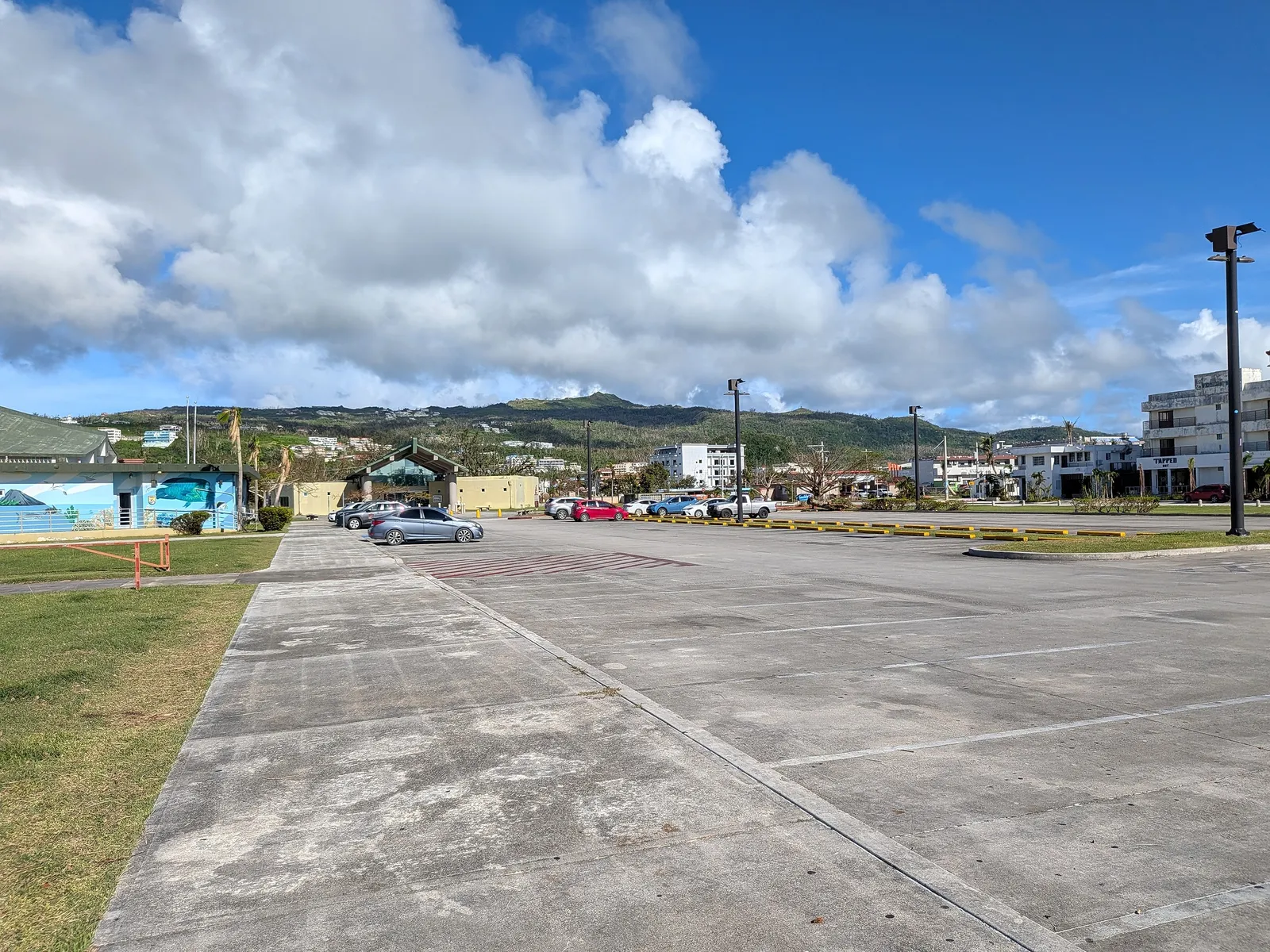 Parked cars near the American Memorial Park visitor center, with Garapan buildings visible in the background