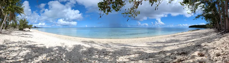 Panorama of Paupau Beach, Saipan, showing the curving white-sand cove and tree line