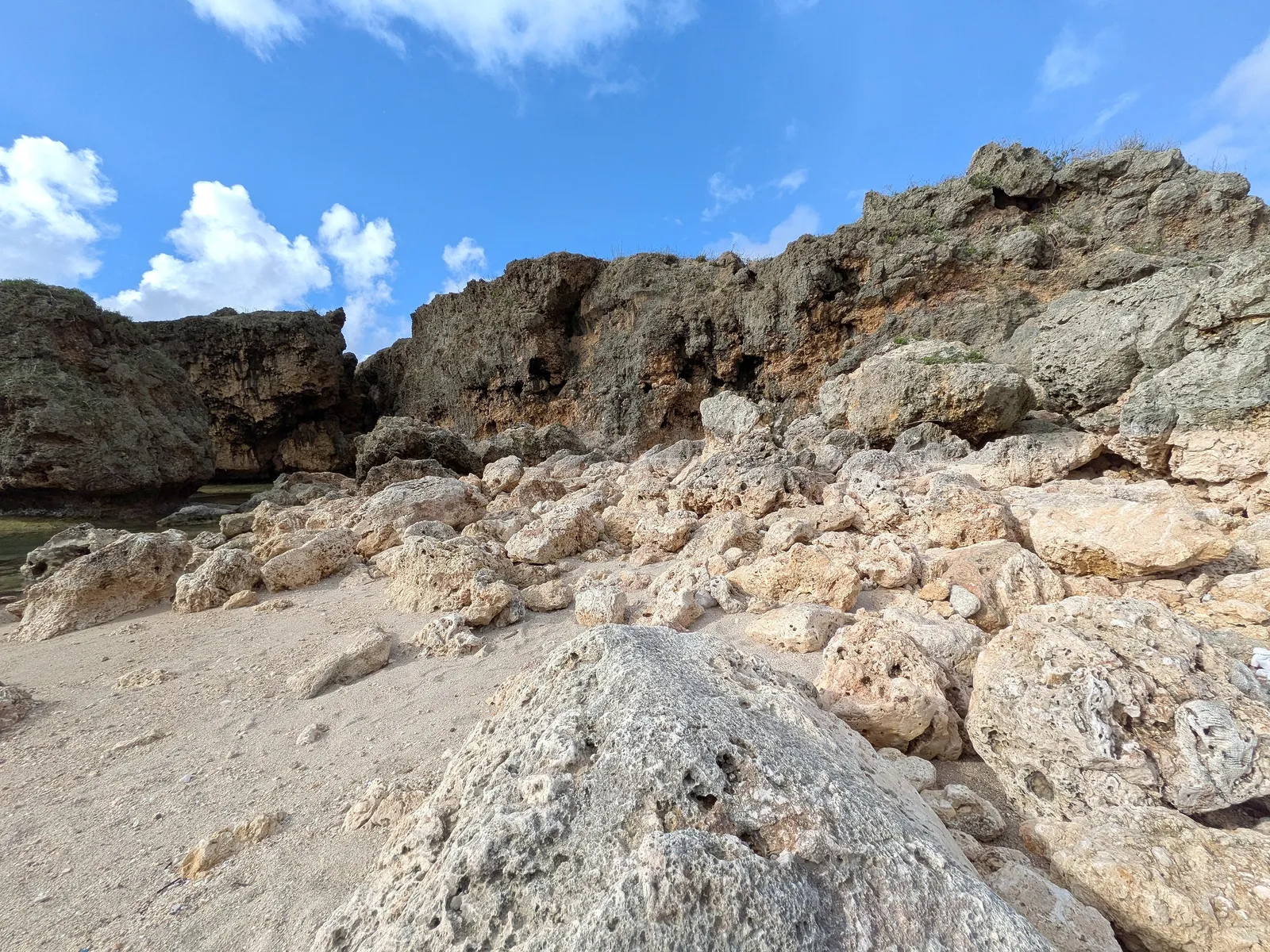 Weathered limestone boulders piled along the shoreline at Unai Fanhang