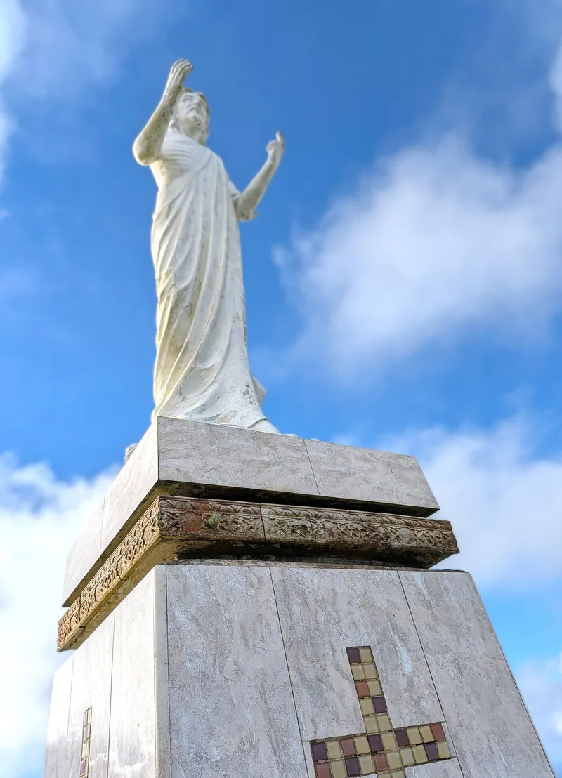 The white statue of Christ at the summit of Mount Tapochau, Saipan's highest point, against a blue sky
