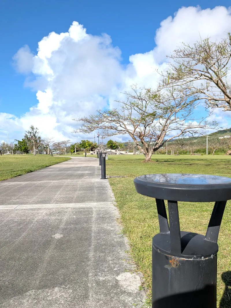 The paved waterfront path at American Memorial Park, lined with bollard lights and benches
